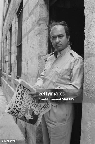Le dessinateur Georges Wolinski lisant le nouveau numéro de Hara-Kiri Hebdo, interdit depuis 1970, le 21 juillet 1981 à Paris, France.