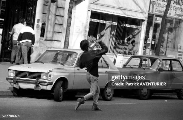 Un manifestant lance une bouteille contre les forces de l'ordre lors d'une manifestation anti-militariste à Paris le 27 mars 1982, France.