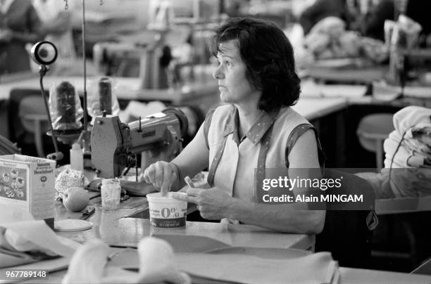 Femme en train de déjeuner dans les ateliers de sellerie de l'usine Renault de Flins le 16 juin 1981, France.