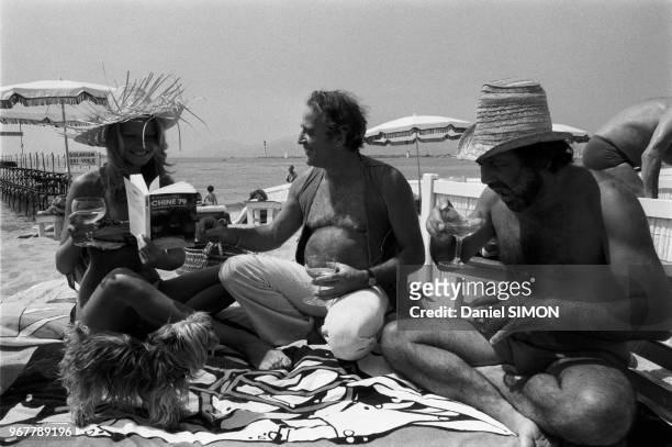 Mimi Coutelier et Jean Yanne boivent un verre sur une plage lors du Festival de Cannes le 14 mai 1979, France.