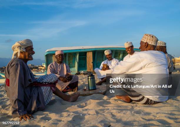 Omani men resting and drinking tea on the beach at sunset, Dhofar Governorate, Mirbat, Oman on May 13, 2018 in Mirbat, Oman.