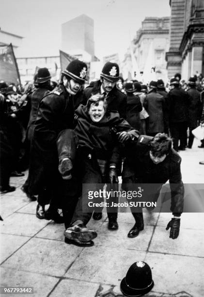 Des policiers britanniques secourent un de leur collègue lors d'une manifestation anti-racisme à Birmingham le 18 février 1978, Royaume-Uni.