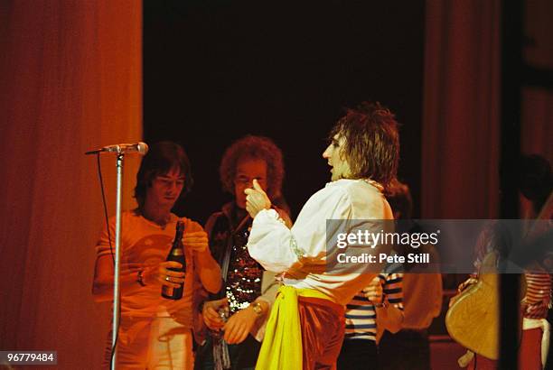 Rod Stewart opens a bottle of champagne on his birthday during his performance on stage at The Playhouse Theatre, while band members Ian McLagan and...