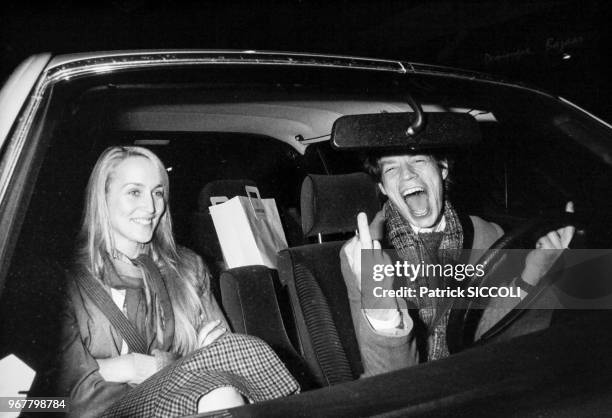 Portrait de la mannequin Jerry Hall et du chanteur anglais Mick Jagger faisant un doigt d'honneur, au volant d'une voiture le 21 novembre 1982 à...