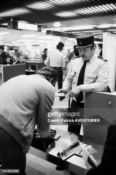 Un douanier vérifie le bagage d'un voyageur dans le cadre du contrôle des changes à l'aéroport d'Orly le 30 mars 1983, France.