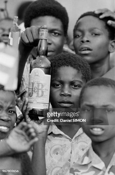 Adolescents avec une bouteille de whisky à Bangui le 13 décembre 1984, Centrafrique.