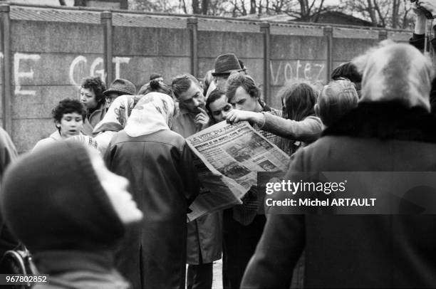 Habitants de Liévin lisant le journal 'La Voix du Nord' devant un tag de la CGT après la catastrophe minière les 27 et 28 décembre 1974, France.