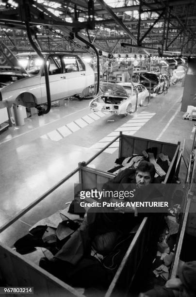 Ouvrier faisant la sieste près d'une chaîne de montage pendant l'occupation de l'usine Citroën d'Aulnay-sous-Bois lors d'une grève le 14 mai 1984,...
