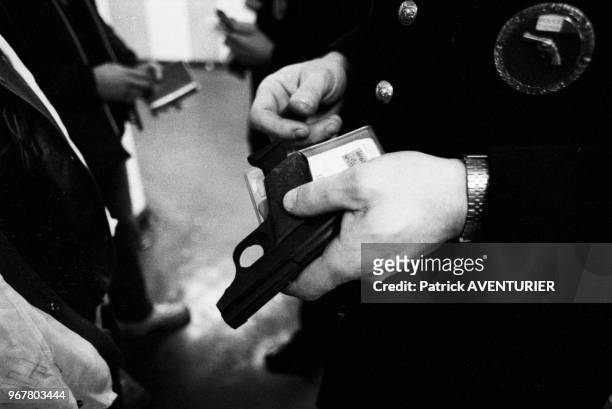 Des policiers viennent de saisir un pistolet lors d'un contrôle dans un couloir du métro parisien le 21 décember 1982, Paris, France.