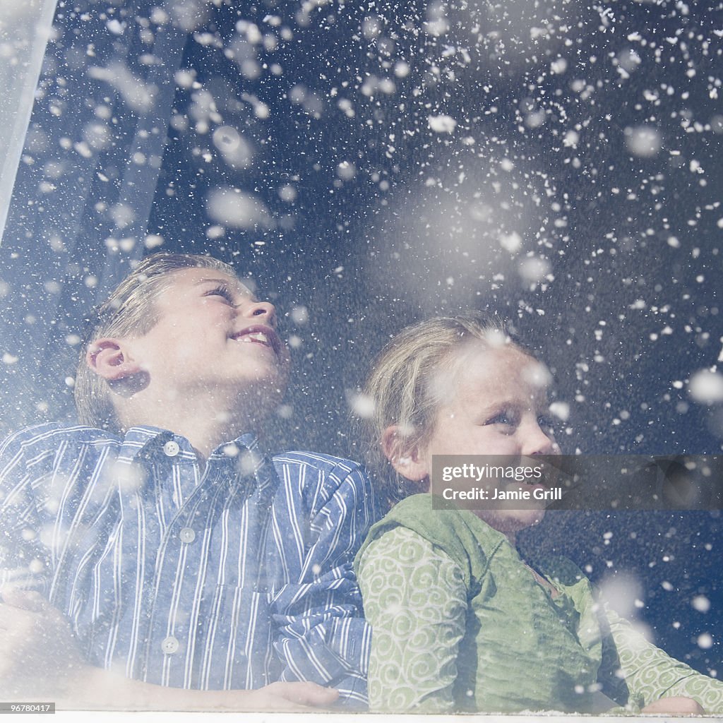 Brother and sister looking out window at snow