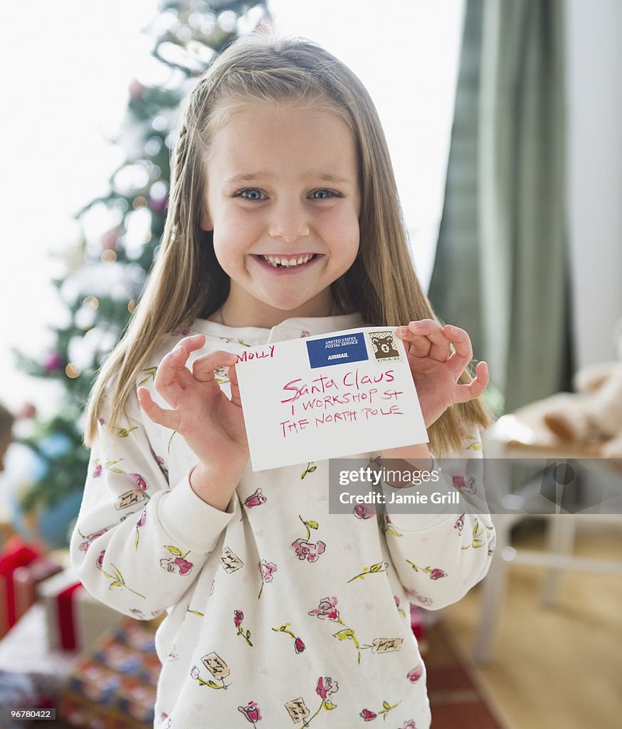 Young girl holding letter addressed to Santa Claus