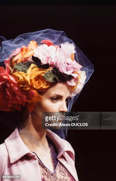 Portrait du mannequin Nadja Auermann portant une coiffure excentrique composée de fleurs du couturier Christian Lacroix lors du défilé de la...