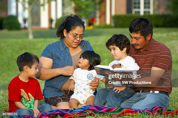 hispanic family outside having picnic - fille lire gazon photos et images de collection