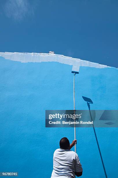 painter painting an exterior wall with blue paint. - cuba painter stock pictures, royalty-free photos & images