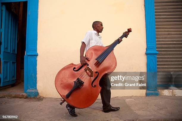 man carrying bass to gig - caribbean musical instrument stock pictures, royalty-free photos & images