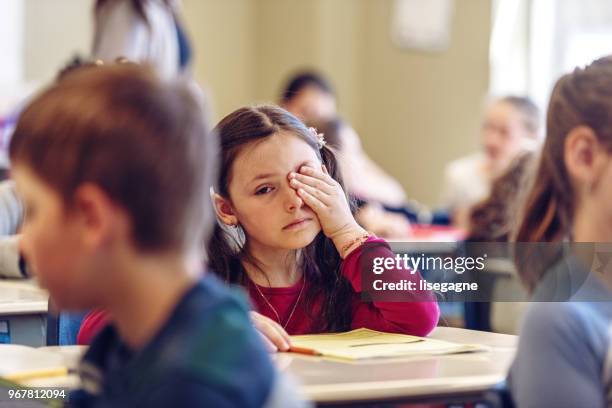traurig schulmädchen in einem klassenzimmer - schulkind stock-fotos und bilder