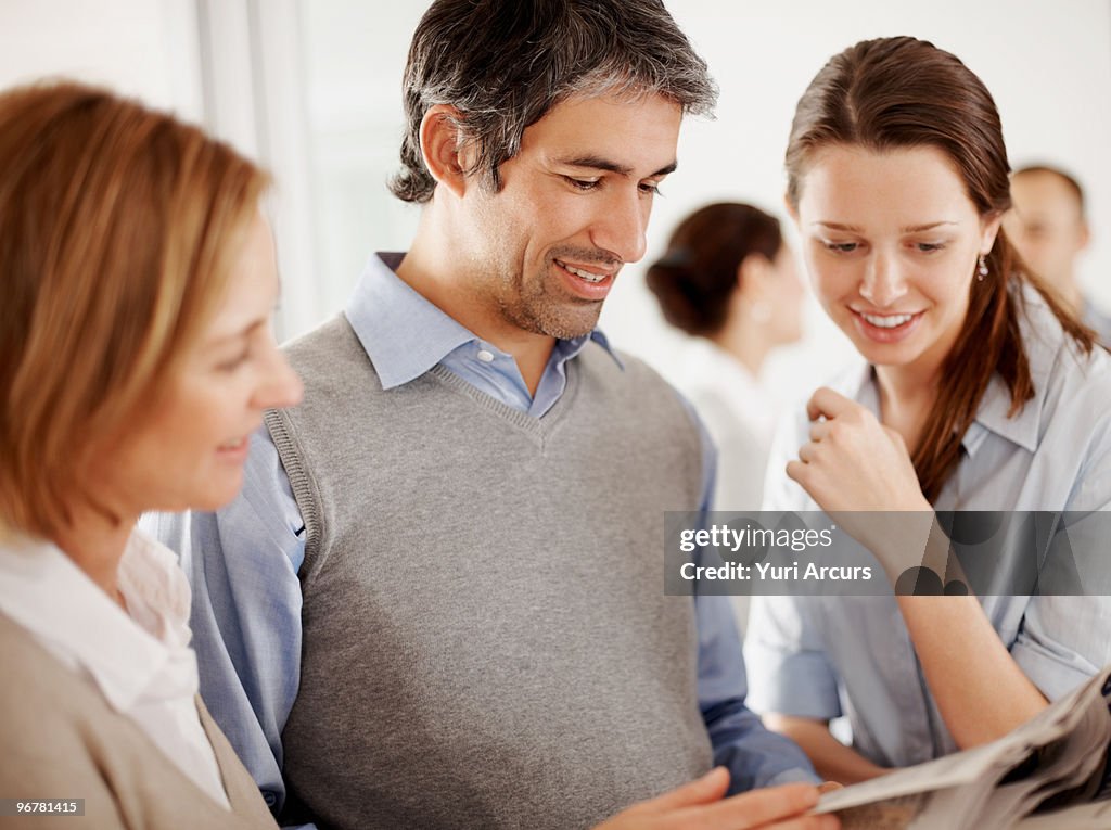 Business man and women reading newspaper together