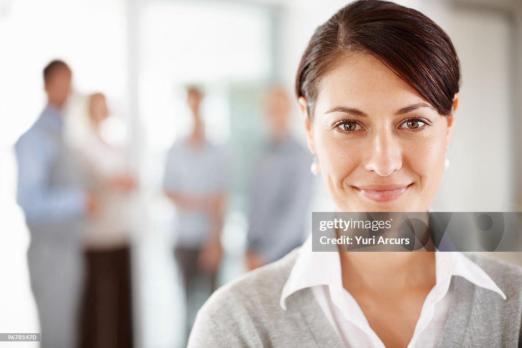 Portrait of a mature business woman with colleagues talking in the background