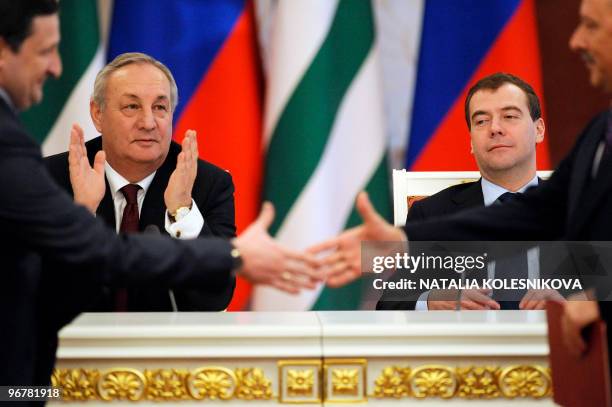 Russian President Dmitry Medvedev and President of Georgia's breakaway Abkhazia region Sergei Bagapsh look on as officials shake hands during a press...
