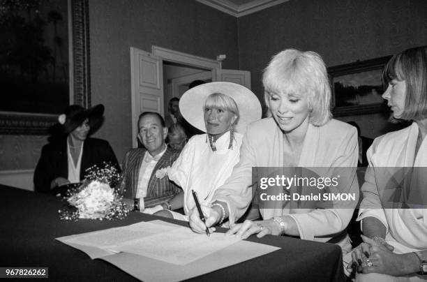 Mireille Darc signe l'acte lors du mariage de Lova Moor et Alain Bernardin à Louveciennes le 28 juin 1985, France.