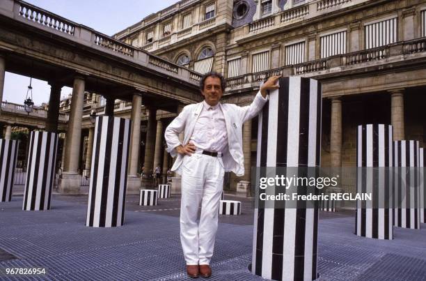 Artiste Daniel Buren pose au milieu de son oeuvre 'Les Colonnes de Buren' installées au Palais-Royal le 30 juin 1986 à Paris, France.