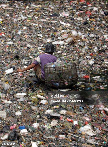 Man collects plastic waste from the soiled river in Jakarta 19 April 2007. Inadequate waste management services in Indonesia's cities contribute to...