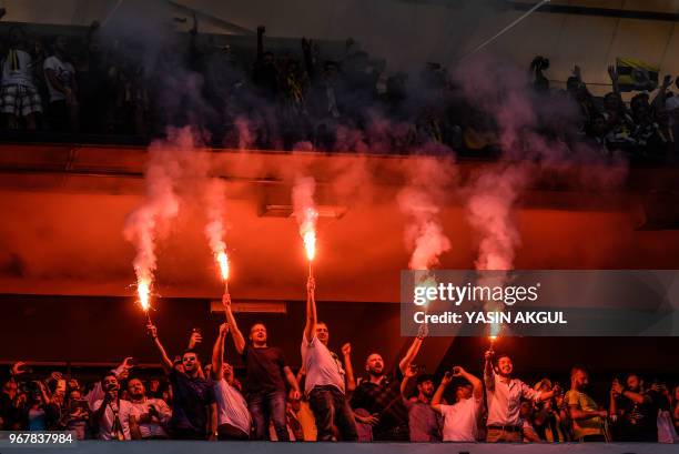 Fenerbahce supporters hold burning flares during a gathering with the newly elected Fenerbahce chairman at the Ulker Stadium in Istanbul on June 5 in...
