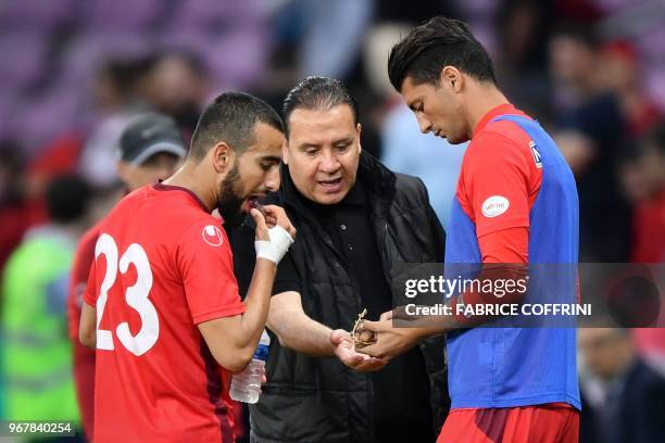 Tunisia's head coach Nabil Maaloul distributes dates to Tunisia's midfielder Naim Sliti and Tunisia's defender Rami Bedoui during the friendly...