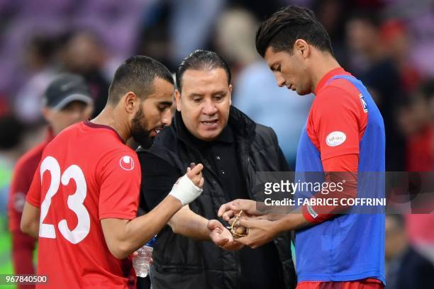 Tunisia's head coach Nabil Maaloul distributes dates to Tunisia's midfielder Naim Sliti and Tunisia's defender Rami Bedoui during the friendly...