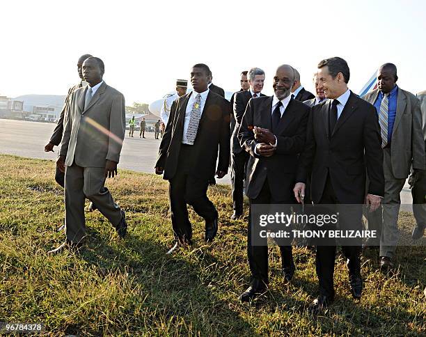 French President Nicolas Sarkozy smiles as he walks with Haitian President Rene Preval as they walk towards a helicopter and get ready to survey the...