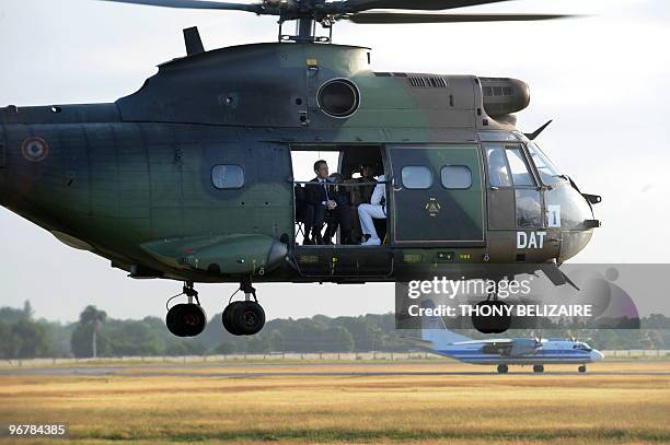 French President Nicolas Sarkozy sits on a helicopter as he gets ready to survey the damaged city with Haitian President Rene Prevel moments after...