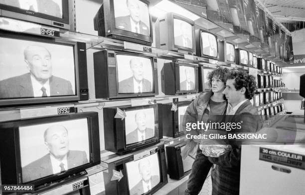 Deux personnes regardent le débat télévisé entre François Mitterrand et Jacques Chirac dans un supermarché de La Défense le 28 avril 1988, France.