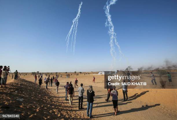Palestinian demonstrators watch as an Israeli quadcopter drone fires tear gas canisters during a protest at the Israel-Gaza border, east of Khan...