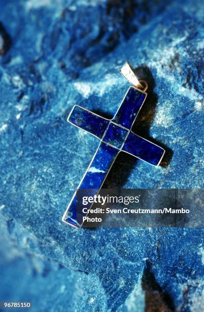 Jewellery cross made of Lapis Lazuli lies on a raw Lapis Lazuli rock in the Flores de Los Andes mine, located at 3,700 meter high in the Andes, on...