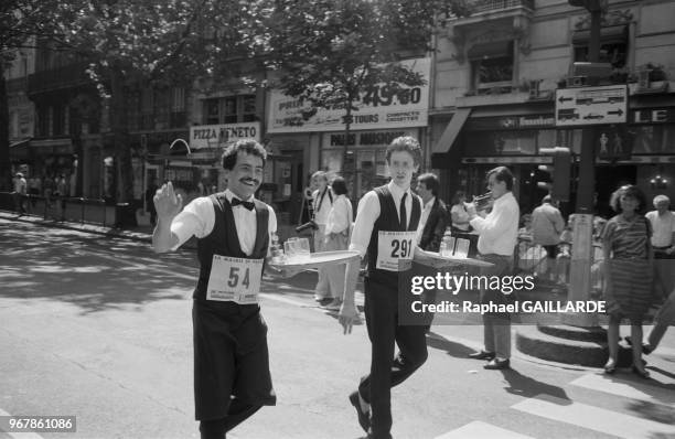 Participants à la course des garçons de café, tenant son plateau en équilibre, le 19 juin 1988, Paris, France.