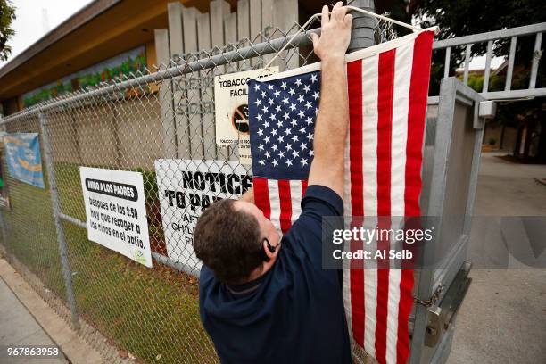 Election Assistant Wayne Martin places an American flag before 7 a.m. June 5, 2018 at the Robert F. Kennedy Elementary School polling place in the...