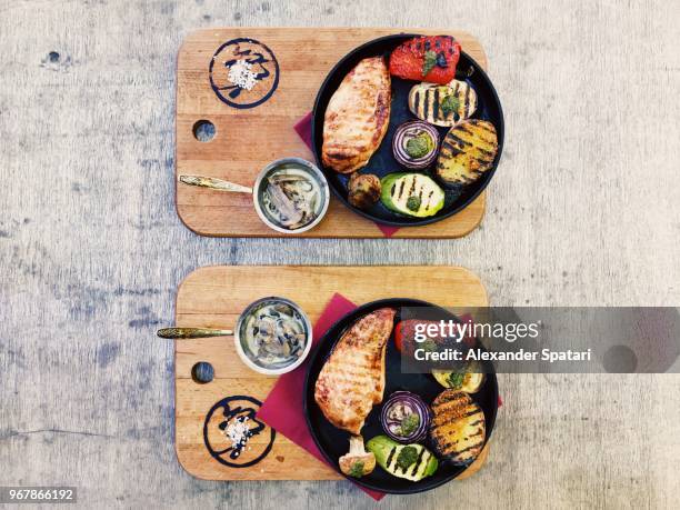 grilled chicken breast and vegetables served in cooking pan on the table, high angle view - frying pan stock pictures, royalty-free photos & images