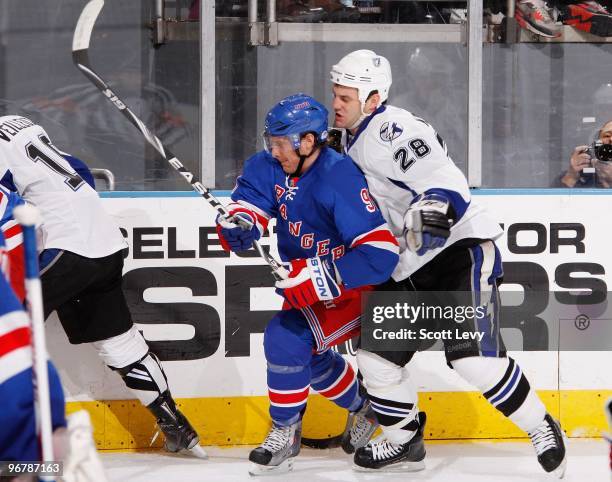 Matt Gilroy of the New York Rangers skates along the boards for the puck under pressure by Zenon Konopka of the Tampa Bay Lightning on February 14,...