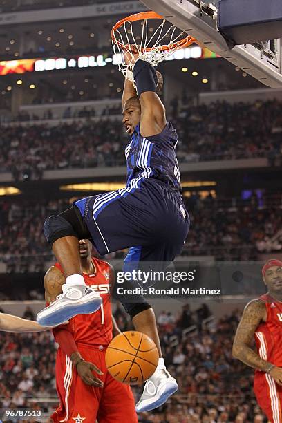 Dwyane Wade of the Eastern Conference hangs on the rim after dunking against Amar'e Stoudemire and Carmelo Anthony of the Western Conference during...