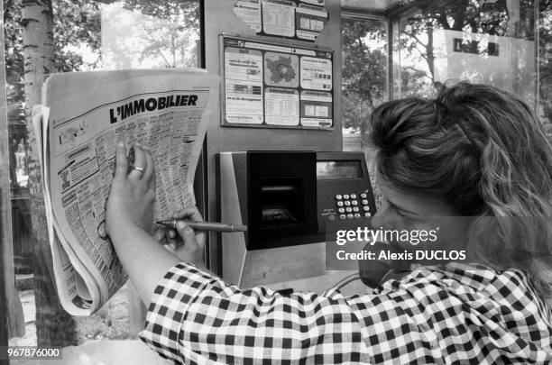 Une jeune femme recherche un appartement via les petites annonces d'un journal, Paris le 23 juin 1987, France.