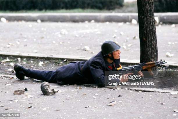 Soldat, fusil-mitrailleur en main, allongé dans la rue, à Bucarest, Roumanie le 23 décembre 1989.