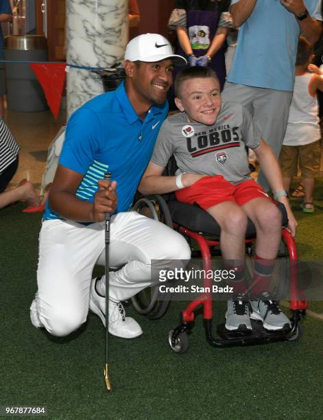Tony Finau plays putt-putt with a young patient from St. Jude Children's Hospital during Golf-A-Round prior to the FedEx St. Jude Classic at TPC...