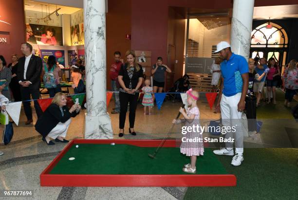 Tony Finau plays putt-putt with a young patient from St. Jude Children's Hospital during Golf-A-Round prior to the FedEx St. Jude Classic at TPC...