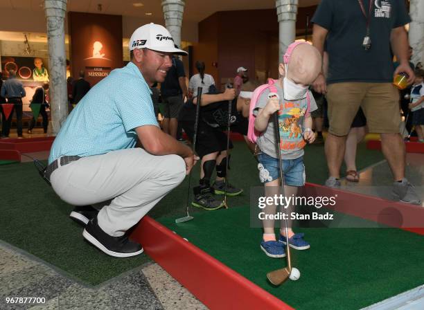 Chez Reavie plays putt-putt with a young patient from St. Jude Children's Hospital during Golf-A-Round prior to the FedEx St. Jude Classic at TPC...