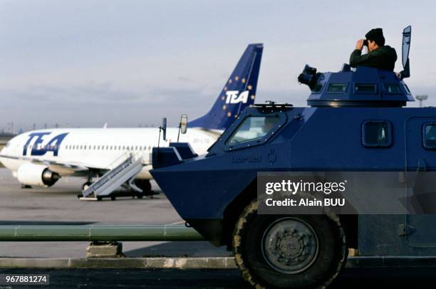 Gendarme surveillant à la jumelle à bord d'un blindé sur l'aéroport d'Orly le 15 décembre 1989, France.