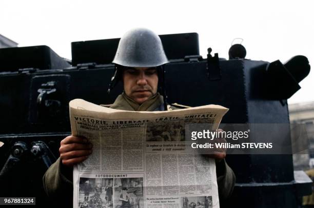 Soldat lisant le journal devant un blindé, à Bucarest, Roumanie le 25 décembre 1989.