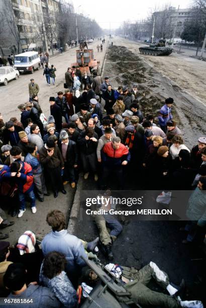 Des Roumains entourent le cadavre d'un agent de la sécurité, à Bucarest, Roumanie le 26 décembre 1989.