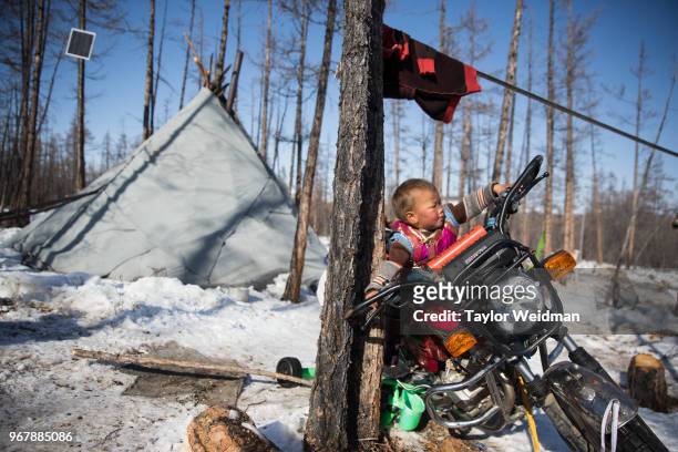 Child plays on a motorcycle outside his family's tipi near Tsagaan Nuur, Mongolia.