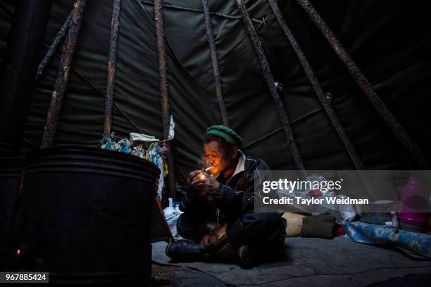 Delger Gorshik lights a cigarette in his tipi near Tsagaan Nuur, Mongolia.