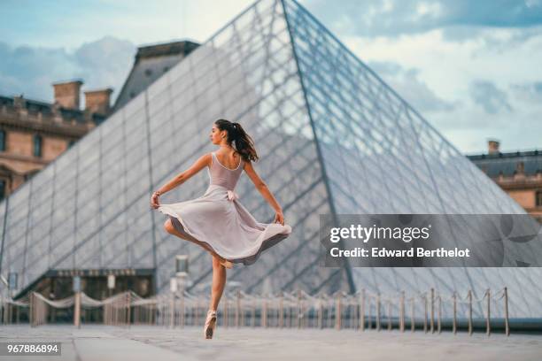 Ballet dancer Amanda Derhy performs a "Pirouette", wears a white leotard, repetto ballerina shoes and a light purple skirt, in front of the Louvre...